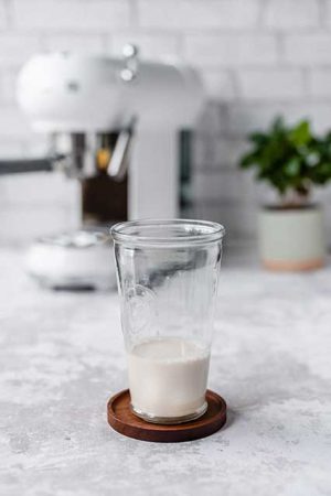 szklanka z mlekiem stoi na drewnianej podstawce