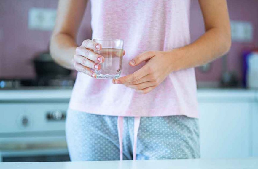 Kobieta ubrana w piżamę trzyma w rękach szklankę z wodą utlenioną do picia która jest trucizną i może doprowadzić do śmierci
