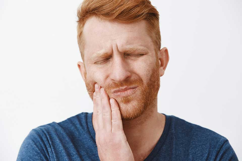 Mężczyzna odczuwa ucisk zęba po leczeniu kanałowym po kilku latach