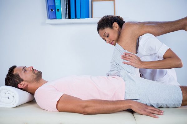Fizjoterapeutka przeprowadza masaż mięśnia czworogłowego uda u mężczyzny, który ma zaburzenia czucia