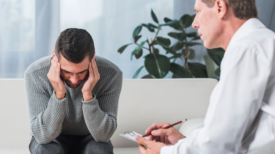 Mężczyzna cierpiący na bóle głowy omawia swoje dolegliwości z lekarzem