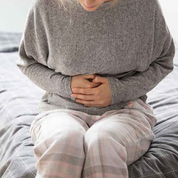 Siedząca kobieta odczuwa ból pochodzący z przewodu pokarmowego