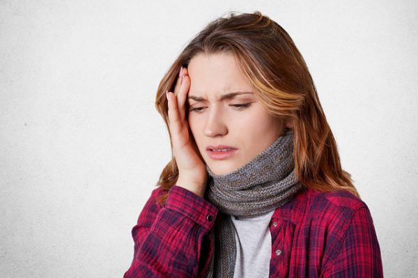 Kobieta cierpiąca na silny ból głowy przy kaszlu